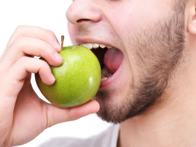 Человек откусывает яблоко 